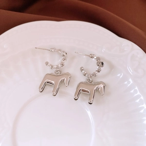 Detailed view of silver horse pendant earrings on a vintage white decorative plate