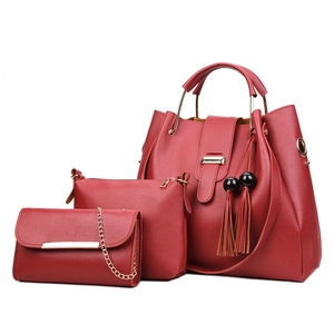 Three-piece red PU leather handbag set with tassels and gold hardware on white background