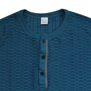 Gros plan du col Henley bleu marine avec texture gaufrée et détail à trois boutons