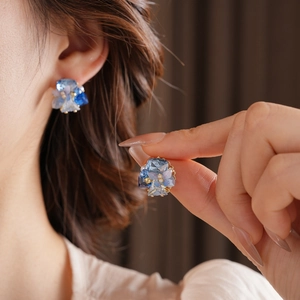 Detail of blue crystal butterfly earrings with gold plating on model and hand