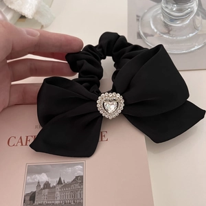 Close-up of a black satin bow scrunchie with a large sparkling crystal heart centerpiece