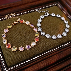 Elegant gold and silver heart bracelets with colorful zircon stones on luxury tray