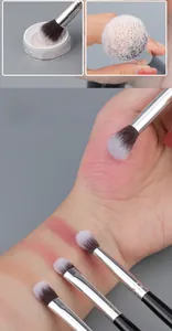 Detail of soft eye blending brush showing synthetic bristles and color swatches on skin