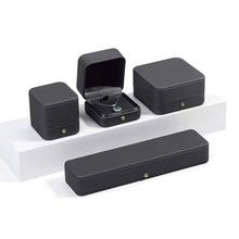 Coffrets à bijoux noir mat haut de gamme pour colliers et bagues sur socle blanc.