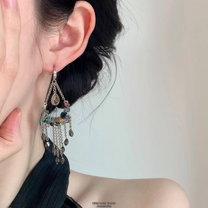 Gros plan sur des boucles d'oreilles vintage à pompons et pierres colorées