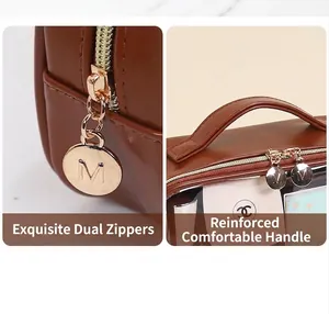 Detail of premium brown leather wash bag featuring dual golden metal M-engraved zippers