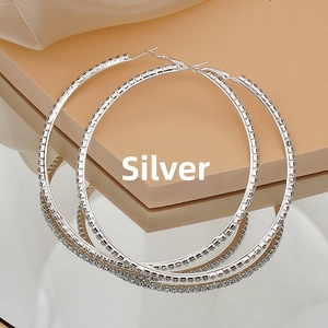 Detailed view of silver oversized hoop earrings with shimmering rhinestones on a mirror