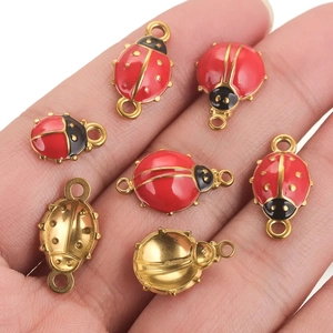 Red and gold ladybug charms for DIY jewelry making shown on palm for scale