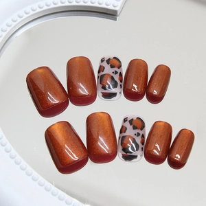 Short round press-on nails with orange cat eye finish and leopard print patterns