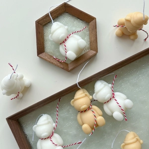 Detailed close-up of cute bear-shaped candles in cream and light brown with knitted hats
