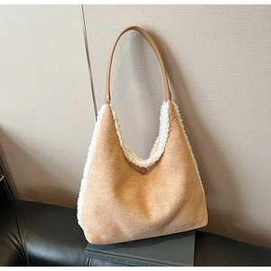 Detail of hobo bag in camel faux suede with white plush trim on a black leather book
