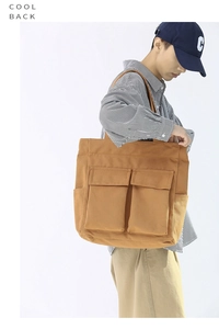 Side view of large khaki canvas tote bag featuring dual front flap pockets and side pockets