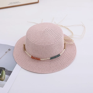 Close-up of pink woven straw sun hat with decorative colorful cord and fine texture