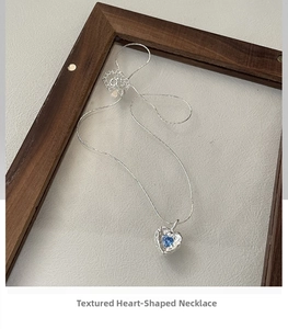 Macro detail of S925 silver heart necklace with blue zircon and textured silver frame