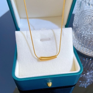 Detailansicht einer goldenen Halskette mit gebogenem Anhänger in einer dunkelgrünen Schmuckbox