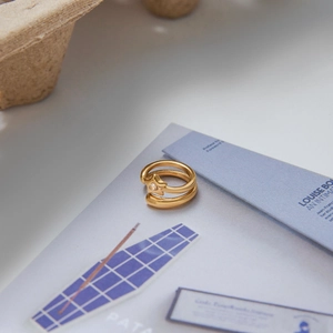 Gros plan d'une bague double dorée avec étoile et zircon sur un fond de papier vintage