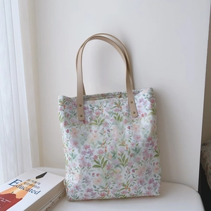 Detail of floral cotton tote bag featuring purple blossoms and premium leather straps