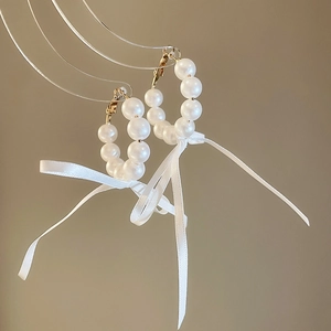 Detail view of elegant French style pearl hoop earrings with delicate white ribbon bow