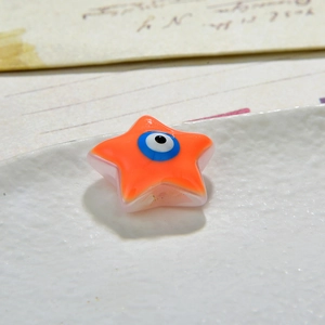 Macro shot of orange star-shaped resin bead with evil eye design for DIY jewelry