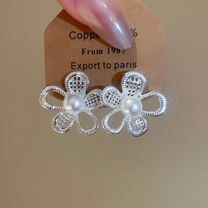Detailed view of hollow flower stud earrings with white pearl center on a copper card