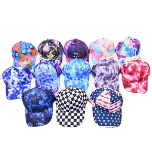 Flat lay of baseball caps featuring tie-dye, galaxy, and checkerboard patterns on white