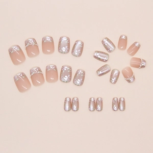 Detail of pink press-on nails featuring floral patterns and delicate pearl embellishments