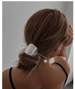 Detail of silver irregular metal hair pin with pearl drop on model hairstyle