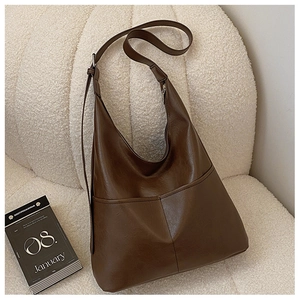 Sac à bandoulière minimaliste en cuir PU marron à grande capacité sur un canapé doux