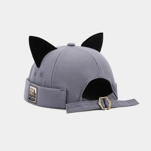 Detail of grey brimless cat ear cap showing canvas texture and metal buckle adjustment