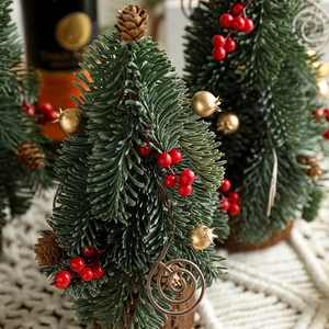 Miniature snowy Christmas tree with red berries and pine cones on a wooden base