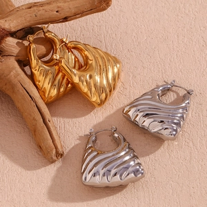 Detail of 18K gold and silver hollow trapezoid earrings with textured wavy patterns