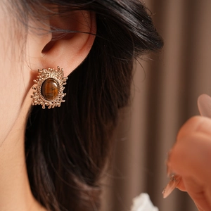 Close-up of a vintage golden tiger eye stone earring worn on a model earlobe