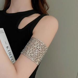 Close-up of a wide hollow mesh upper arm cuff in silver on a model's arm