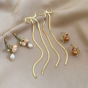 Macro shot of silver flower pearl earrings set on silk fabric with elegant metal textures