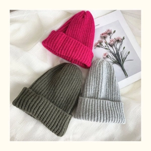 Detailed knit texture of ribbed beanie hats in magenta, olive green and light grey colors