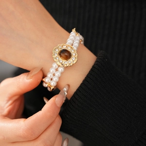 Dettaglio del bracciale vintage a più strati in perle con chiusura a fiore in occhio di tigre