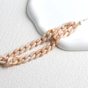 Detail of beige marble acrylic phone strap with golden metal clasps on white background