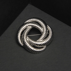 Macro detail of silver twisted knot brooch featuring intricate spiral texture on metal