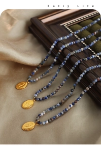 Macro view of blue natural stone beaded necklaces with gold miraculous medal pendants