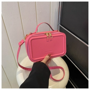 Detailed macro view of rose pink mini suitcase crossbody bag with golden zippers