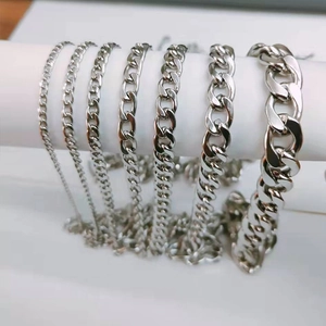 Detail showing various sizes of silver Cuban link chains on a white cylinder stand