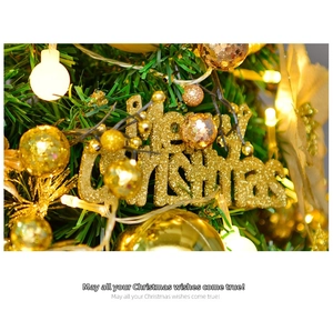 Close-up of golden glitter Merry Christmas sign on a decorated pine tree with warm LED lights
