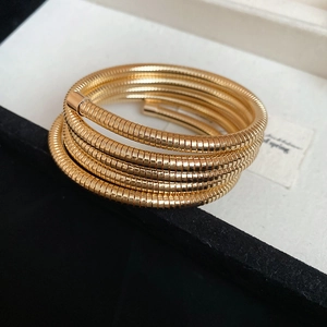 Macro shot of gold spiral textured bracelet with multi-layered metal wire coil design