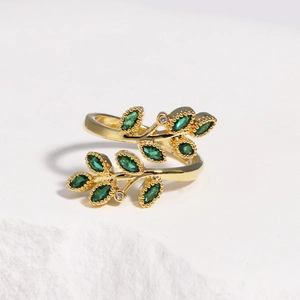 Détail macro de la bague branche dorée avec feuille émeraude et texture perlée fine