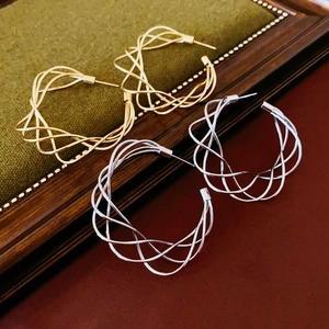 Orecchini a cerchio geometrici intrecciati in oro e argento su espositore vintage