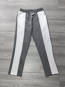 Dettaglio dei pantaloni jogger patchwork grigi e bianchi con elastico e coulisse