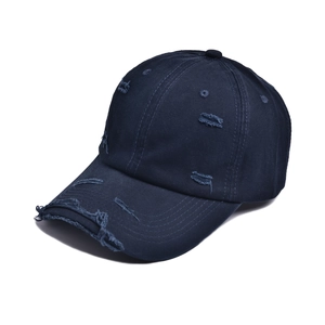 Close-up of navy blue distressed baseball cap featuring vintage frayed holes and cotton twill texture