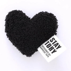 Detail of black plush heart accessory with white fabric label on white background