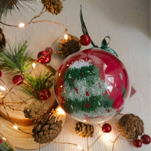 Festive Christmas ball ornament with a red and green knitted tree inside for holiday decor