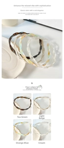 Detail of twisted acetate hairbands in amber and cream tones on a ceramic plate